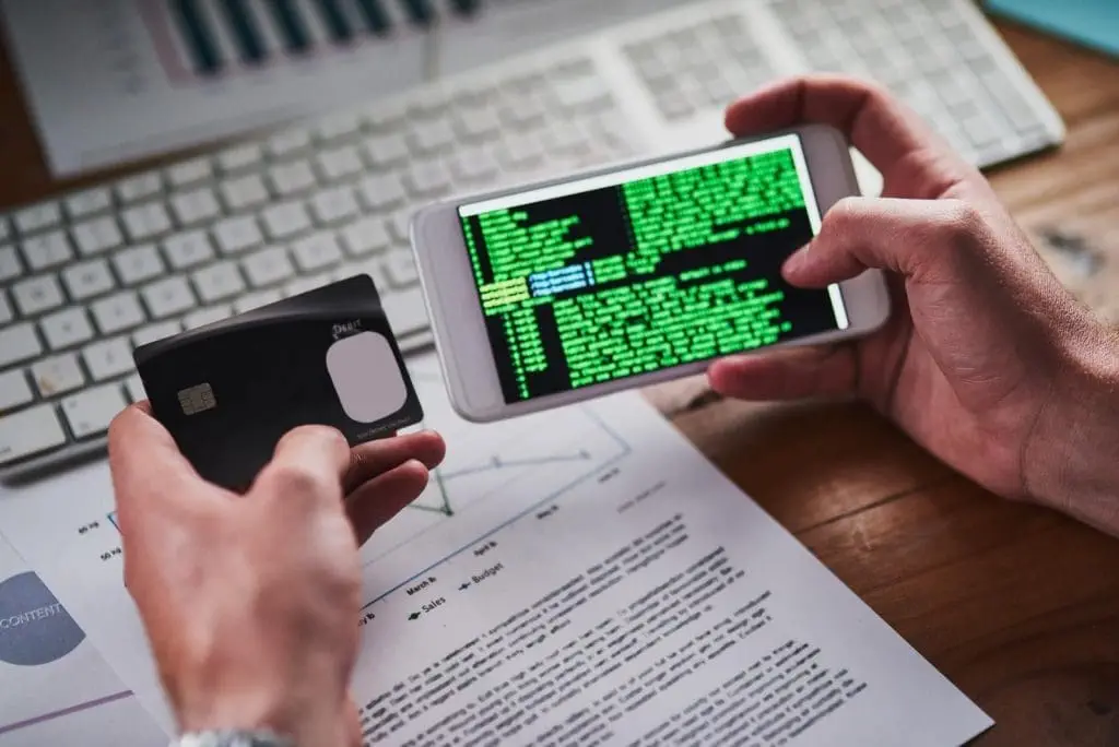 Is Data Science Easier Than Computer Science? A person holding his credit card in one hand and doing programming on his phone in the other hand.