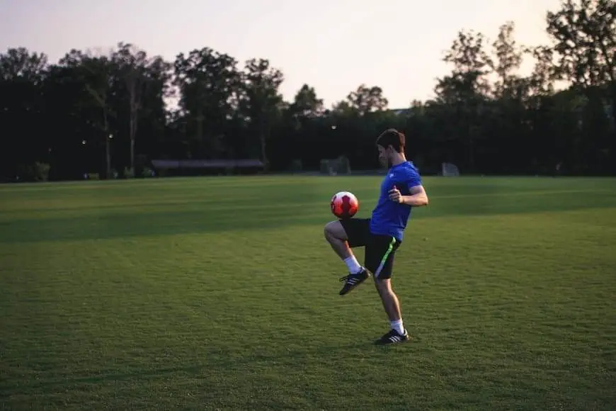 What Does FT Mean in Soccer? Man juggling the soccerball with his knee on grass field