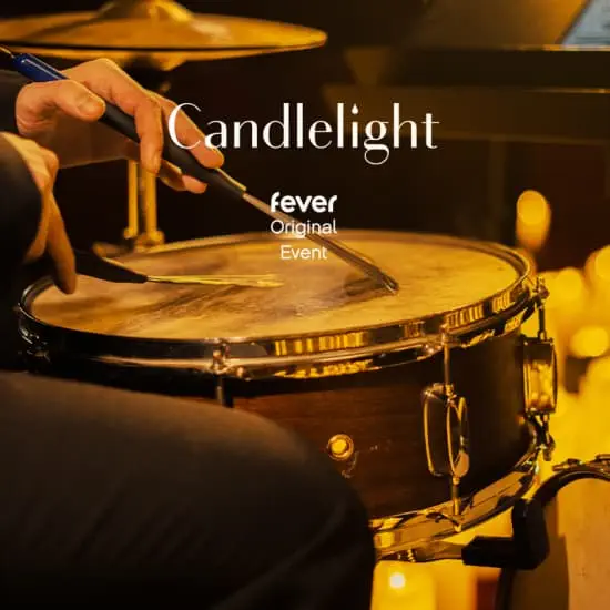 Cover footage from Fever of a musical event by Candlelight featuring the Birth of Soul. A faceless image of a person playing a drum with dimmed golden light.