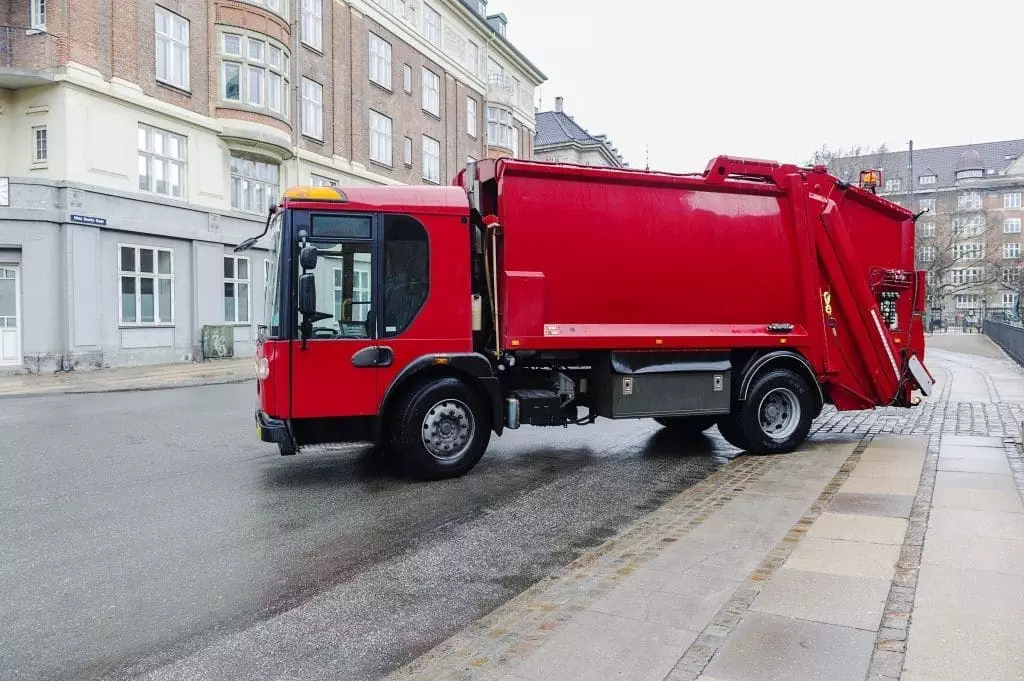 Red trucks collecting weekly garbage