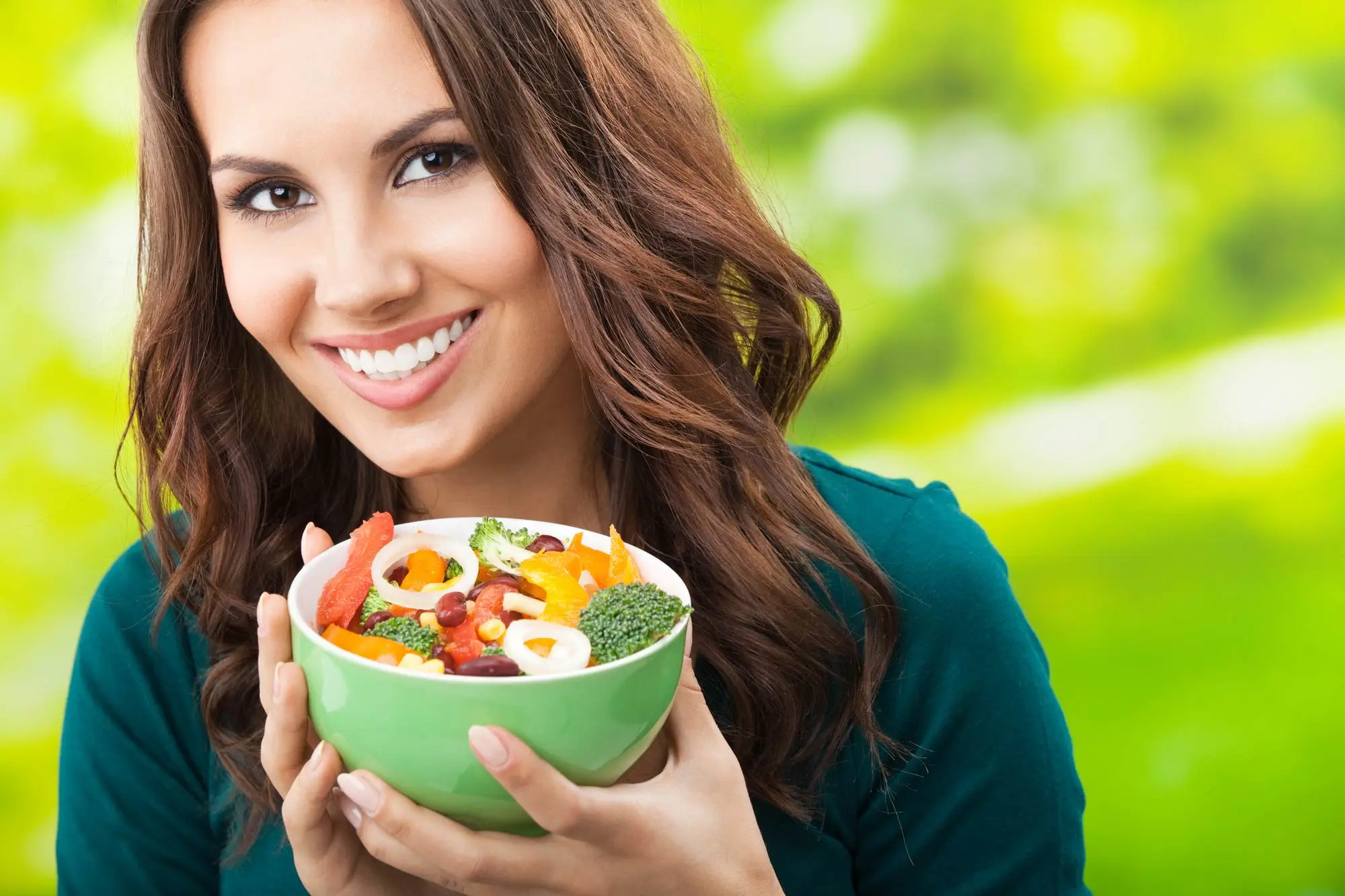 What Is the Health Benefit of Avocado Seed? 10 Benefits to Know A smiling woman showing a bowl of diet salad without avocado, one should avoid avocado seeds while being on a diet.