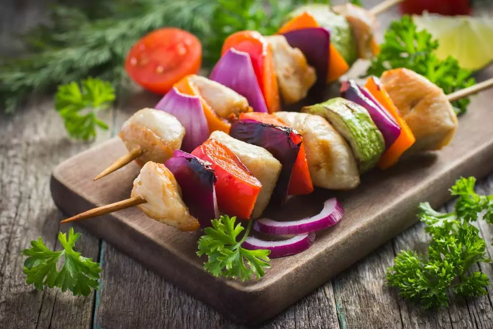 A close-up view of grilled Chicken with vegetable kebabs with cilantro decoration on a platter. Is chicken good for health?