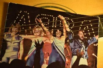 A picture of a group of people performing on the stage and ABBA written in the background. A presentation of an Open-Air Musical Tribute to ABBA in North York.