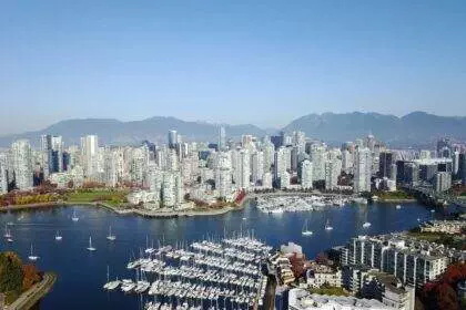 An aerial view of Vancouver City. A view of a seaport and high-rise buildings on the land. There are multiple attractions in Vancouver to catch sight of.