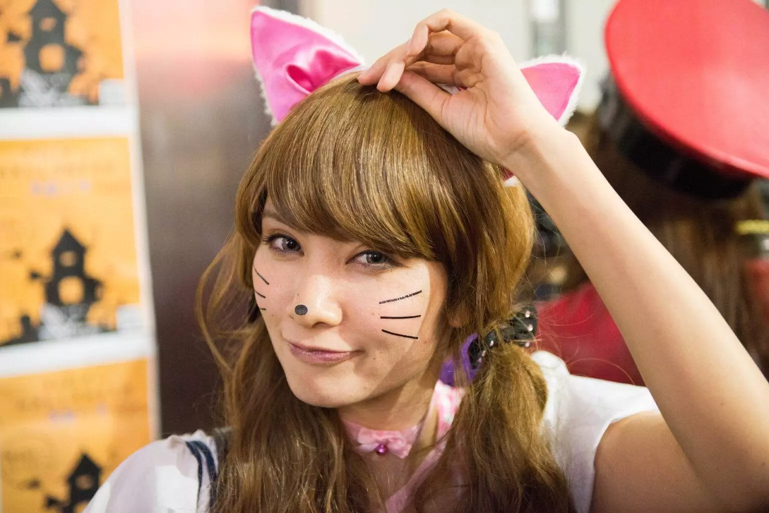 A woman posing while wearing a cat ear headband and makeup.