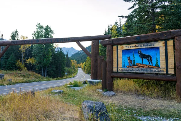 A view of a small road of the Bow valley parkway with a board sign at the entrance.