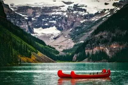 A scenic view of Lake Louise with 2 red canoes.
