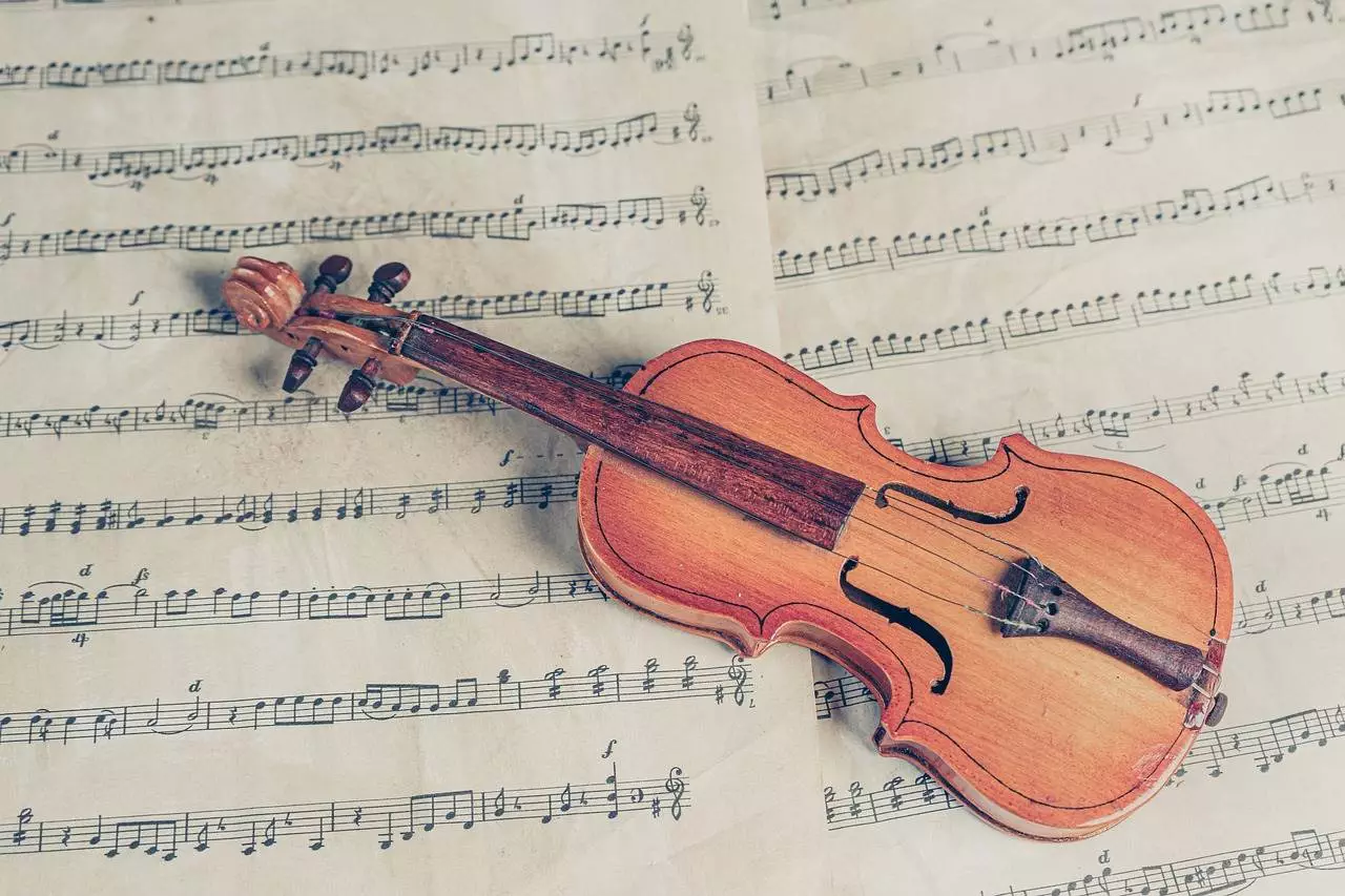 A close-up of a small violin is kept on a musical note.