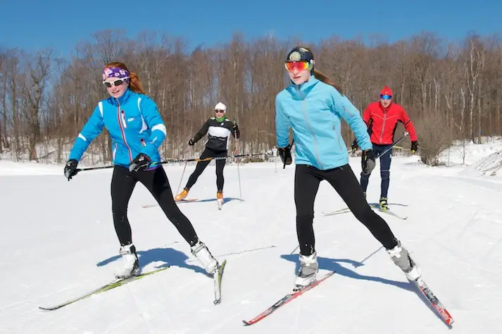 Everything You Can Do at the Blue Mountains Scenic Caves? A group of people skiing on the snow on a sunny day.
