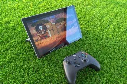 A tablet and game controller lying on the grass.