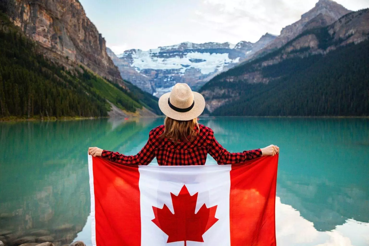 Why is Lake Louise So Blue? A woman holding a flag beside a lake.