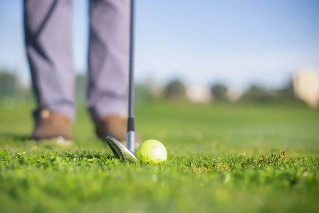 How to Fit Yourself for Golf Clubs A person ready to hit the gold ball on the ground.
