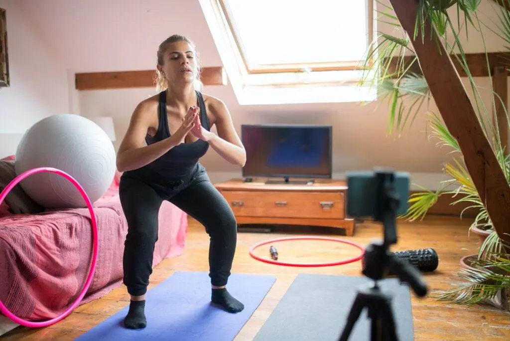 Your Options When Starting an Online Training Biz A woman recording herself while doing exercise.