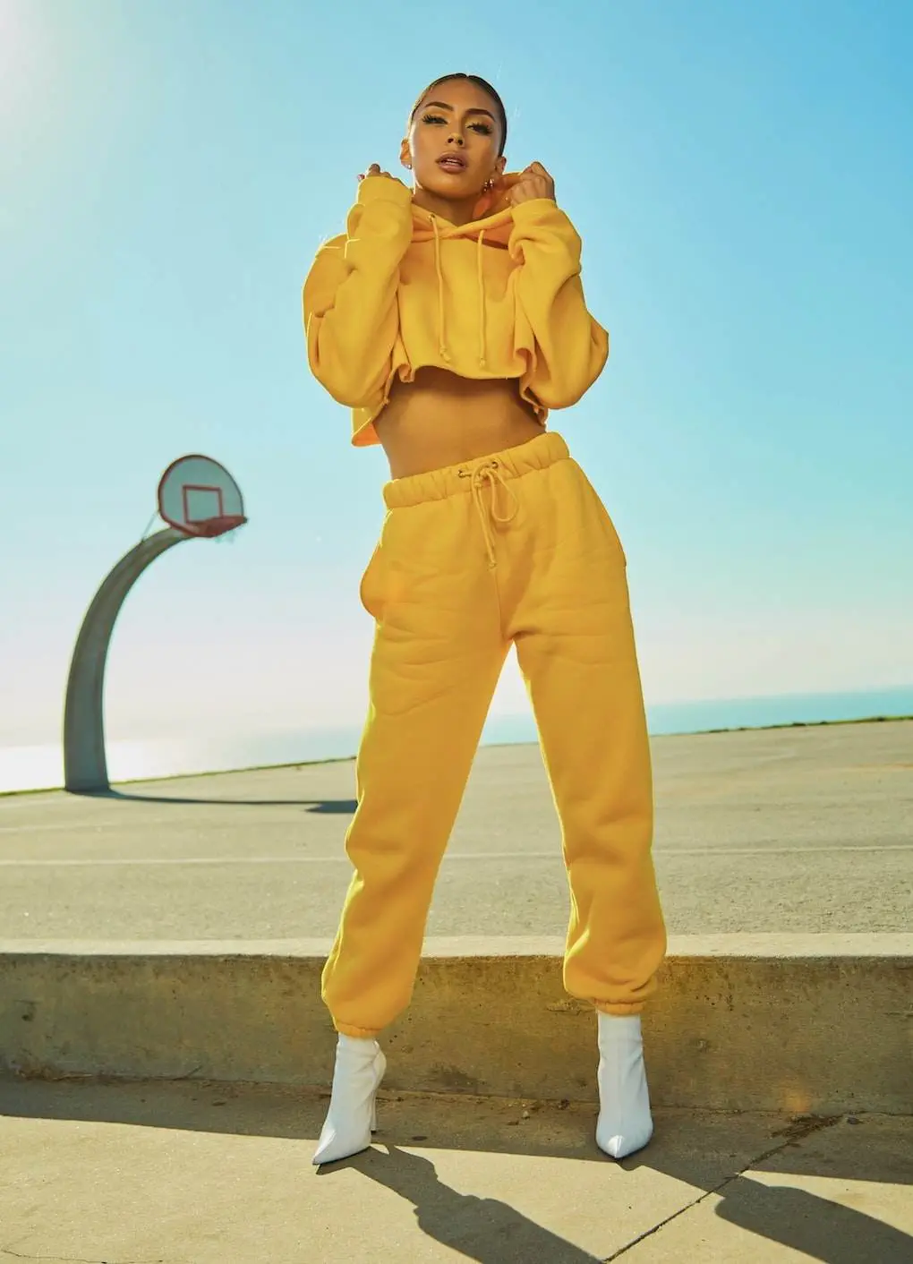 What to Wear to a Hockey Game? A woman wearing a yellow Tracksuit and white-heeled boots.