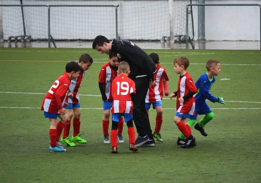 How Long Is a Soccer Game? Children playing soccer with the coach