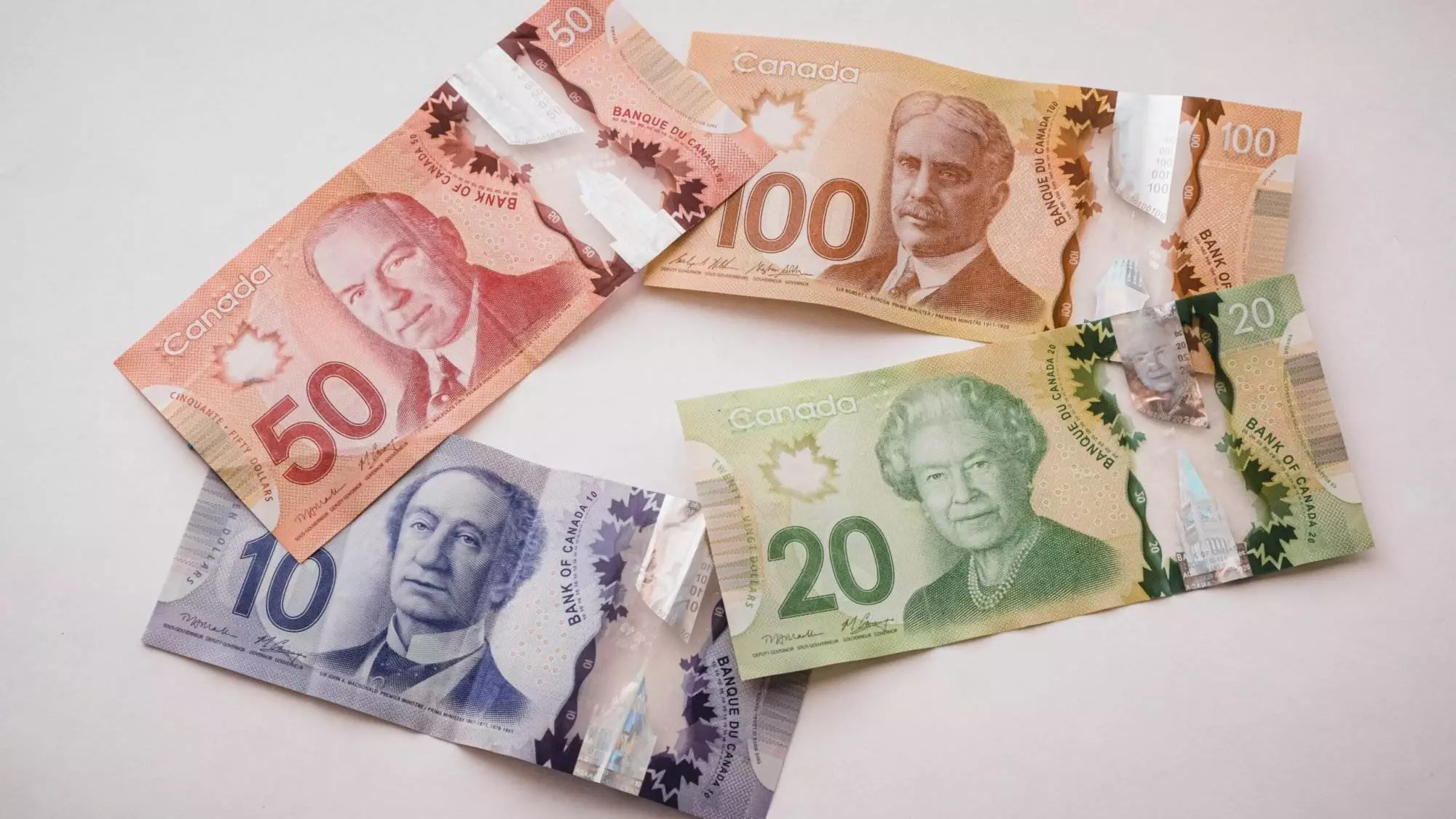 A group of Canadian dollars lying on a plain white surface.