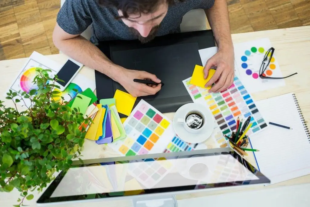 Is a Graphic Design Degree Worth It A top view of a person working with some colour palette and a laptop.