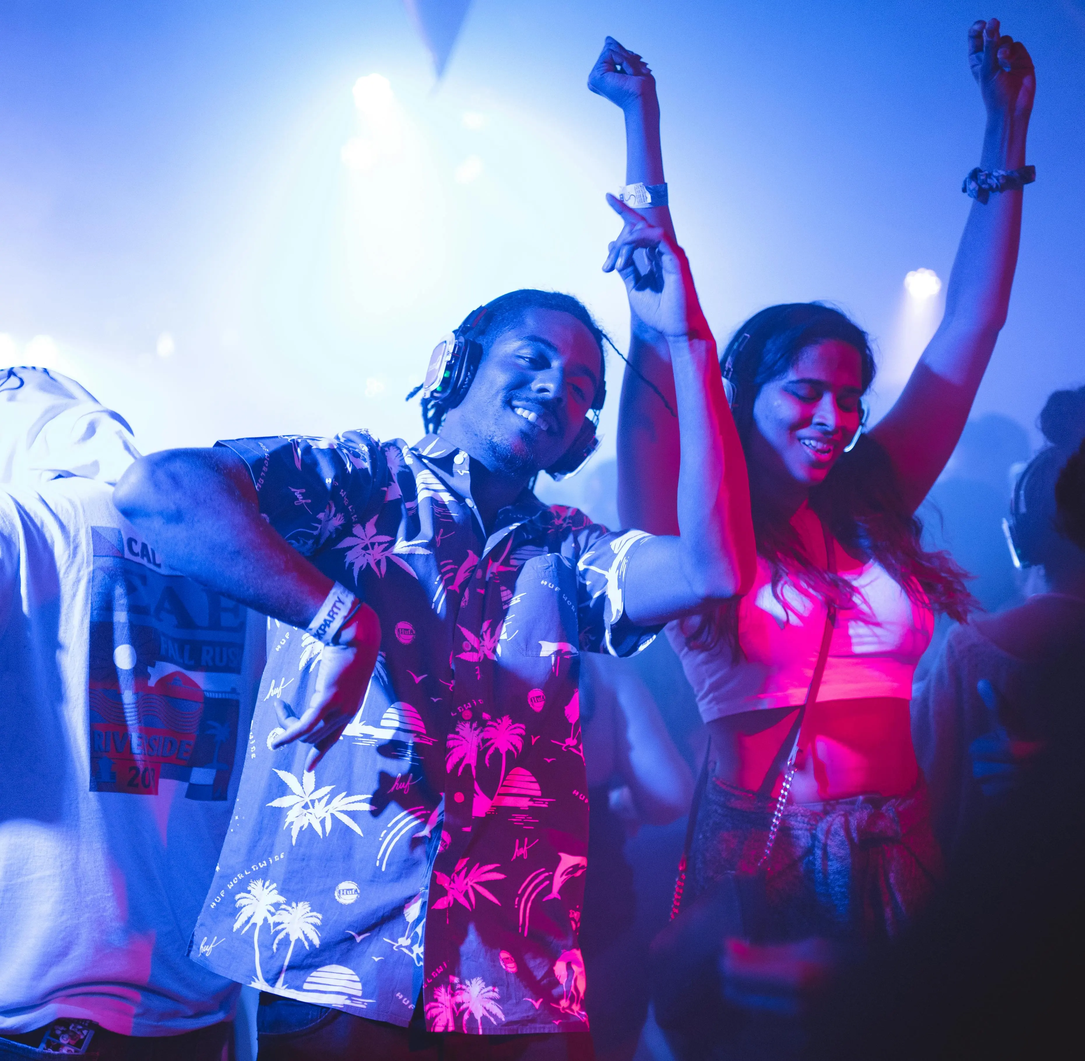 A black man wearing a beachy shirt dancing with headphones on in one of the Vancouver nightclubs.