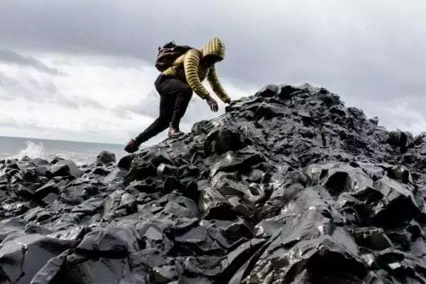 man-wearing-hoodie-and-black-pants-climbing-up-pile-of-rocks-1058958